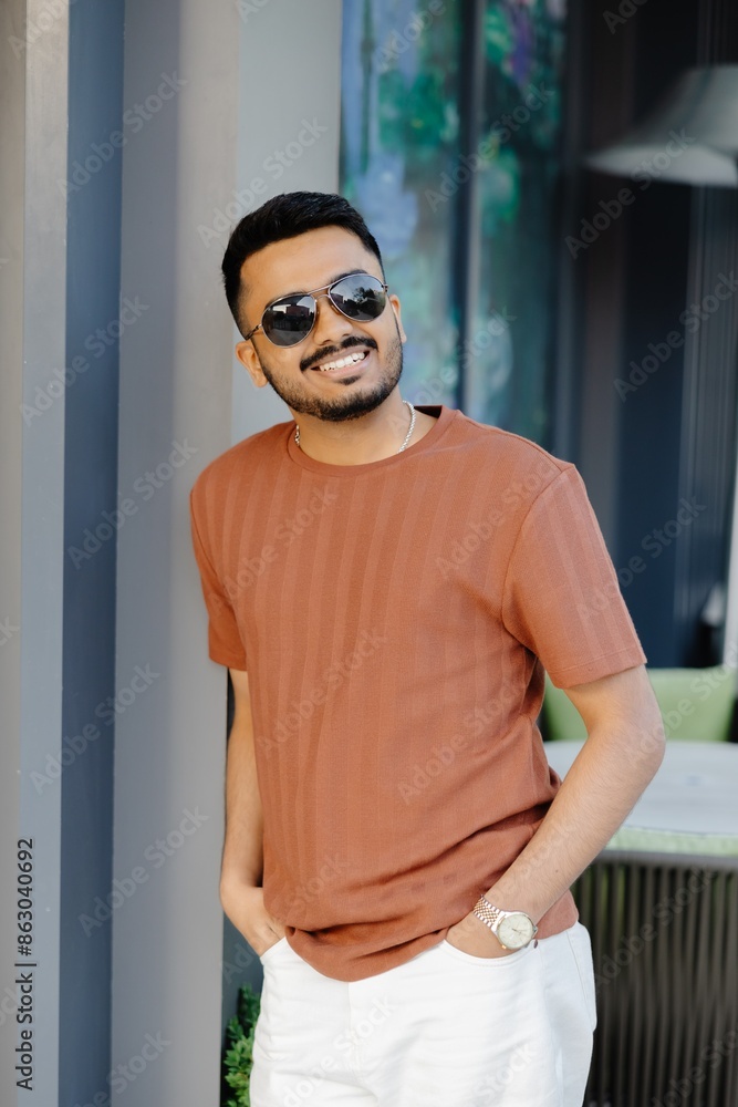 Young Indian smiling man looking to the side with a confident look, standing outside on the street Young Indian smiling man looking to the side with a confident look, standing outside on the street