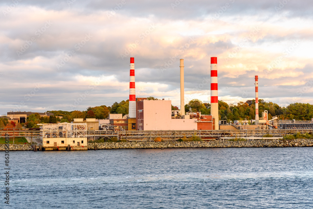 Riverside power station with tall smokestacks under dramatic sky at sunset in autumn Riverside power station with tall smokestacks under dramatic sky at sunset in autumn