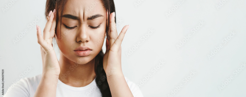 Terrible headache. Girl touching her temples, feeling stress on gray background Terrible headache. Girl touching her temples, feeling stress on gray background