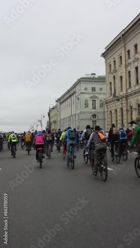 Saint-Petersburg, Russia - June 20, 2022: Vertical Full HD video. Back view. Large group of cyclists riding down street road. Historical city center. Mass bike ride. Day. Cloudy sky. Peloton. Cycle photo