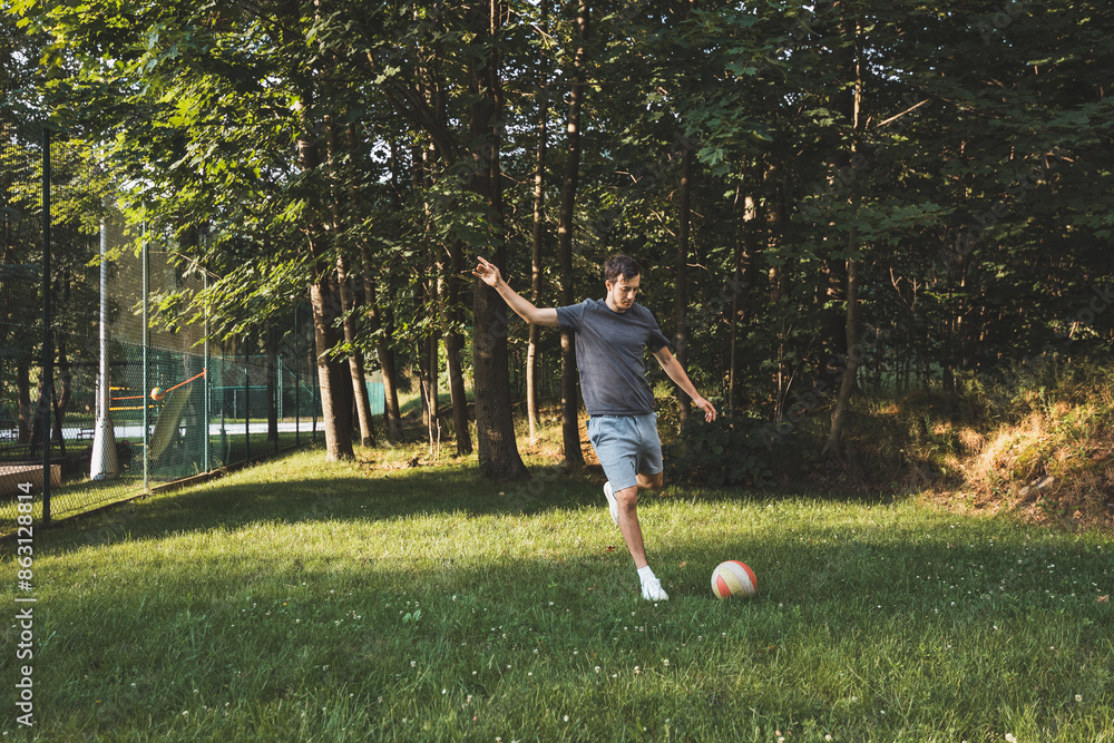 Black-haired athlete plays a friendly football match on the lawn. Amateur sport. Man playing with a ball. Dribbling practice. Sport lifestyle