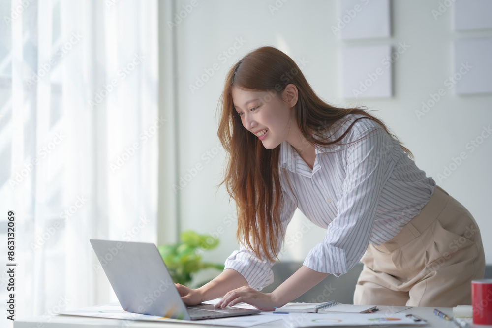 Young professional woman working in a modern office setting, using a laptop at her desk, focused on a project and enjoying her work environment. Young professional woman working in a modern office setting, using a laptop at her desk, focused on a project and enjoying her work environment.