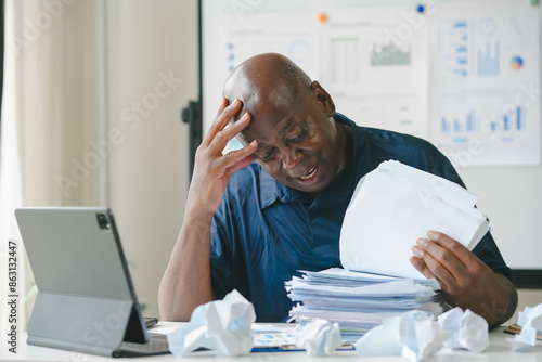 Foto Man frustrated with paperwork and reports at desk, surrounded by crumpled paper
