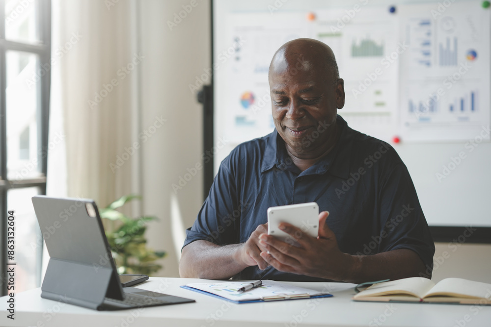 Mature professional working on tablet and laptop in modern office, analyzing data charts and graphs, multitasking with technology. Mature professional working on tablet and laptop in modern office, analyzing data charts and graphs, multitasking with technology.