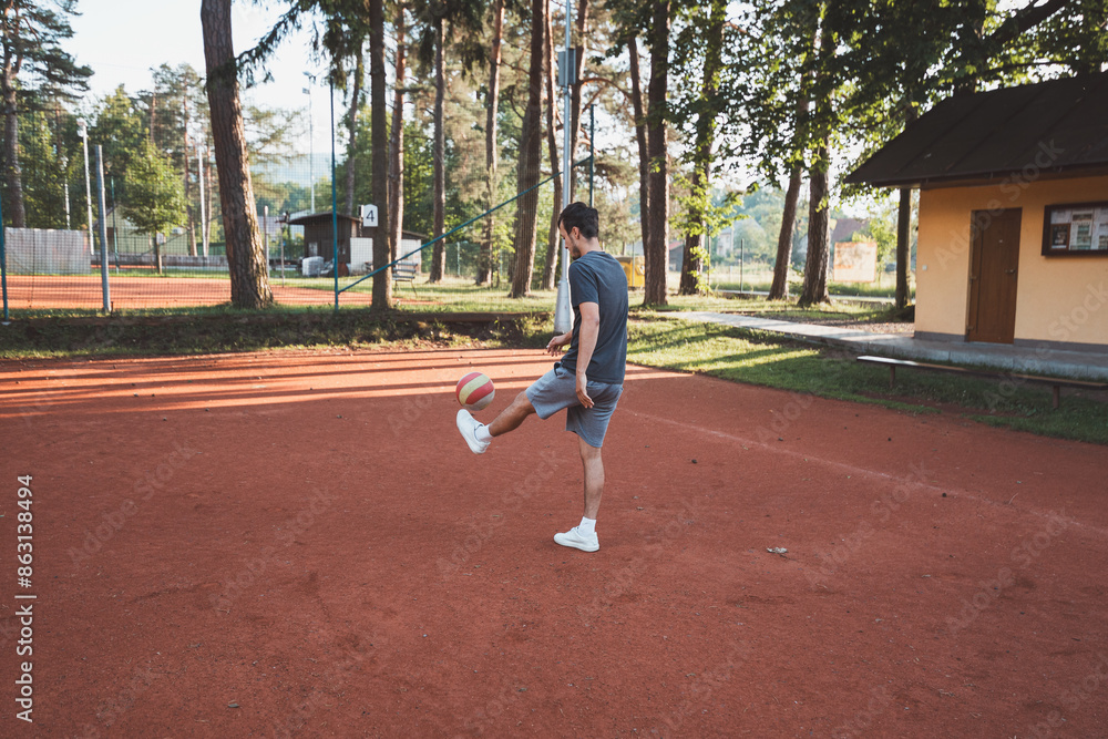 Black-haired athlete plays with a balloon on a clay court. Amateur sport. Individual football training. Soccer. Kicking, striking, passing and dribbling Black-haired athlete plays with a balloon on a clay court. Amateur sport. Individual football training. Soccer. Kicking, striking, passing and dribbling
