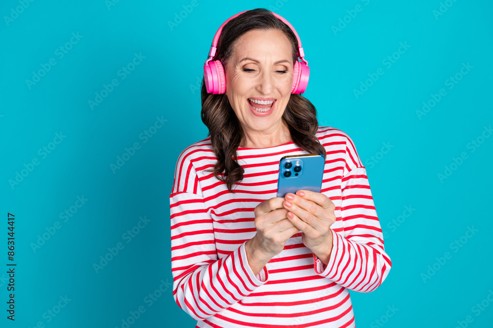 Portrait of nice aged lady headphones smart phone wear pullover isolated on turquoise color background Portrait of nice aged lady headphones smart phone wear pullover isolated on turquoise color background