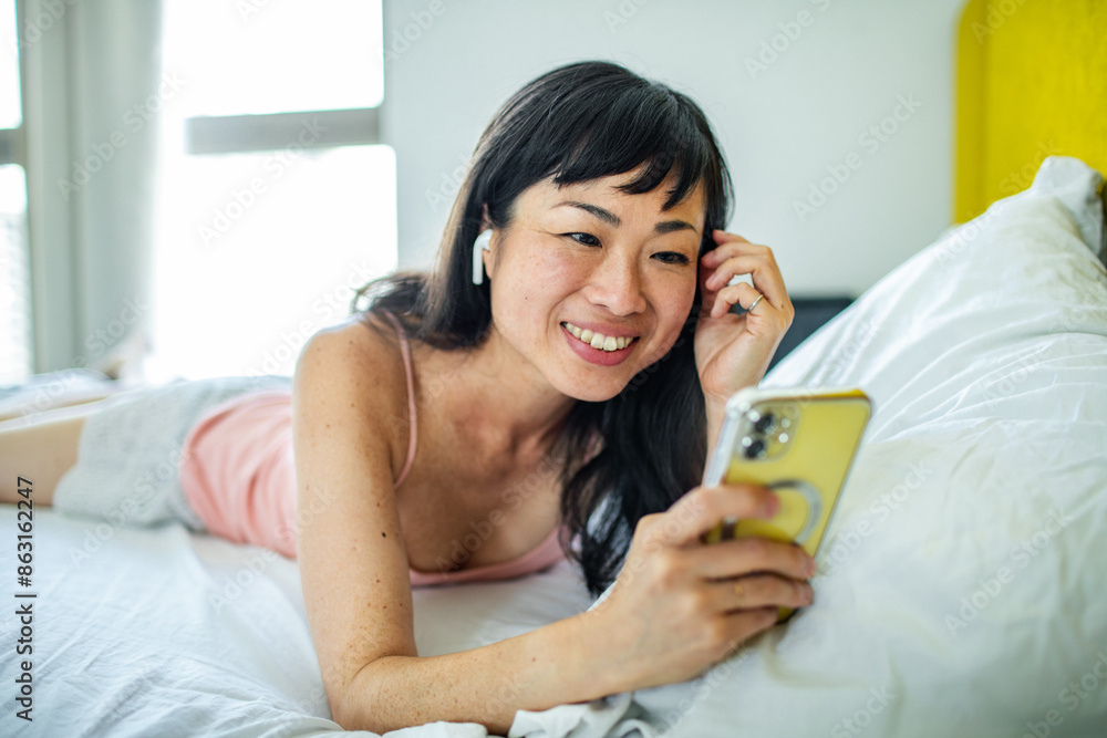 Smiling Asian woman using smartphone at home Smiling Asian woman using smartphone at home