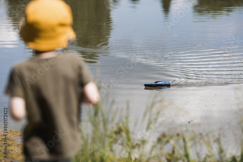 Quadro em tela A 5-year-old boy in a yellow panama hat launches a radio-controlled boat in a pond