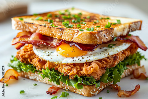 A sandwich with bacon, egg, and lettuce on a white plate. The sandwich is cut in half and has a generous amount of lettuce on top