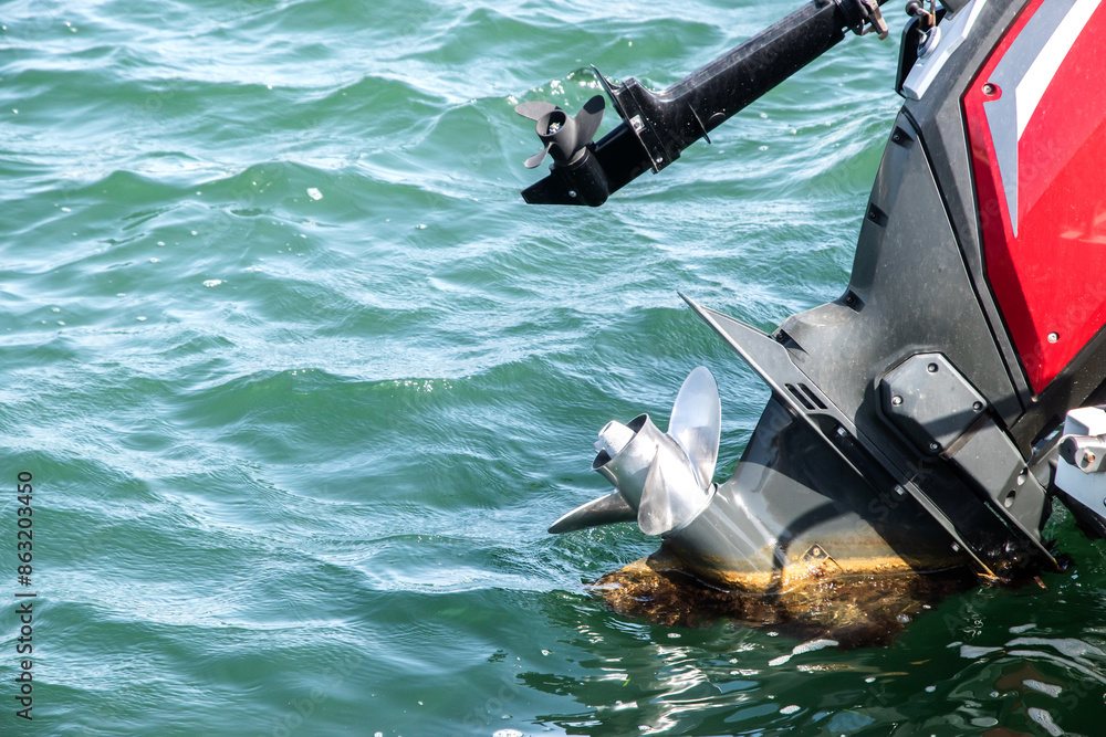 Naklejka premium Outboard engine propeller on motorboat closeup on sea waters background