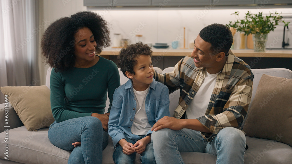 African American happy family portrait couple man father male dad mom woman mother female sitting indoor couch talking speak cuddle stroking head little boy child son kid parent tenderness living room African American happy family portrait couple man father male dad mom woman mother female sitting indoor couch talking speak cuddle stroking head little boy child son kid parent tenderness living room