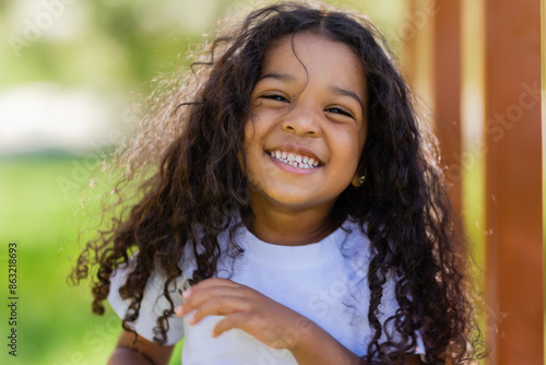 Fotografie little mulatto girl in a white T-shirt on a summer walk