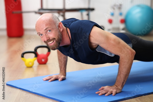 Mann macht Liegestütze auf blauer Matte im Fitnessstudio photo