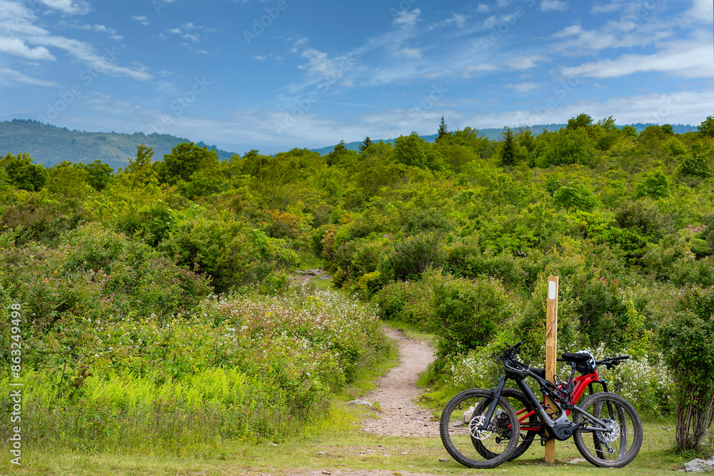 Two mountain bikes are secured to an Appalachian Trail marker at the intersection with the Rhododendron Trail in Grayson Highlands State Park so that the riders can explore the trail on foot. Two mountain bikes are secured to an Appalachian Trail marker at the intersection with the Rhododendron Trail in Grayson Highlands State Park so that the riders can explore the trail on foot.