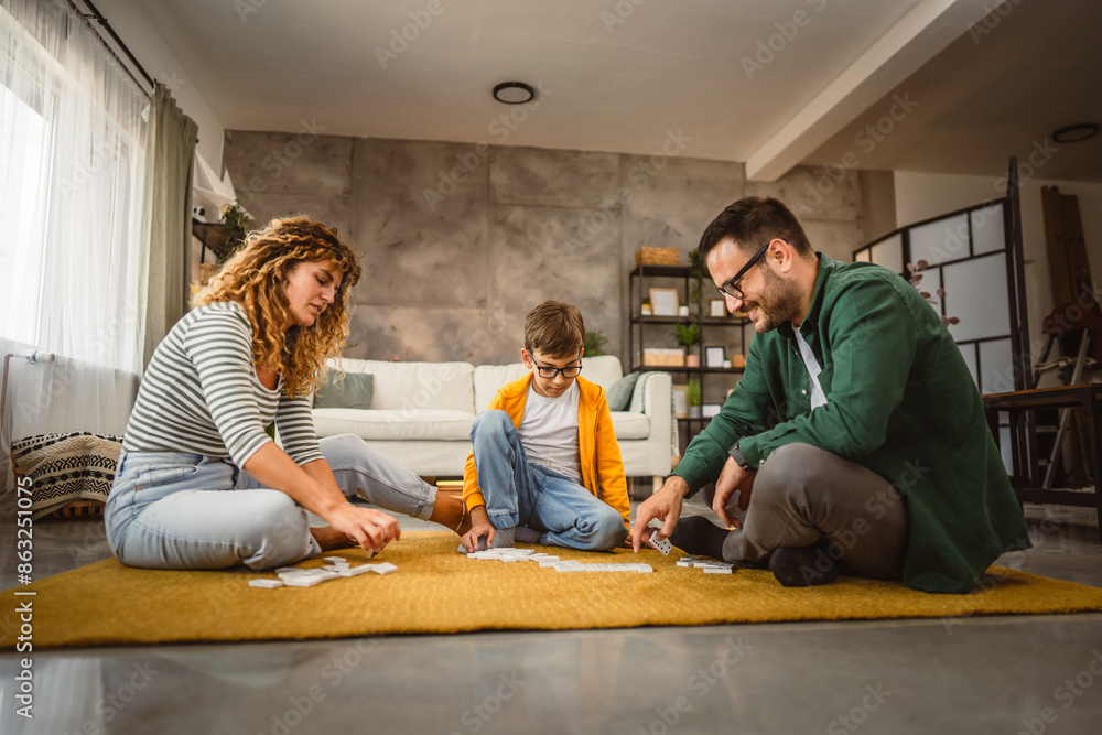 Dad, mum and son play dominoes together on the floor at living room Dad, mum and son play dominoes together on the floor at living room