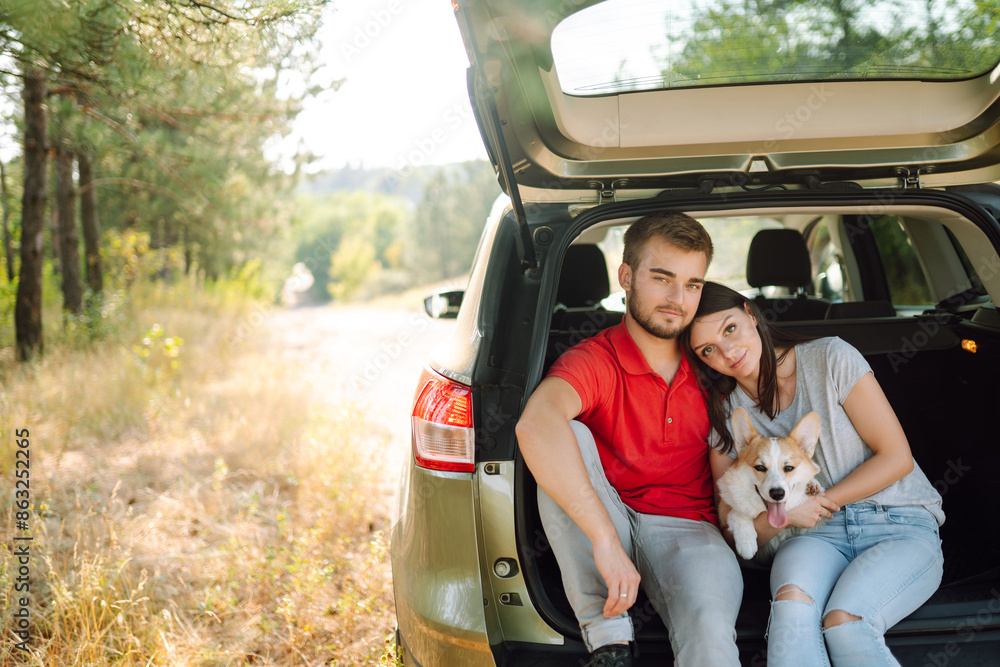 Family traveling with pet. Young couple with their dog in back seat of car while traveling. The concept of an active lifestyle, travel, love and vacation. Pet and human. Family traveling with pet. Young couple with their dog in back seat of car while traveling. The concept of an active lifestyle, travel, love and vacation. Pet and human.