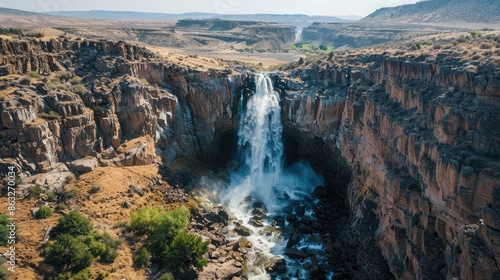 Wallpaper Mural A powerful waterfall flowing into a deep canyon, with rugged cliffs and sparse vegetation Torontodigital.ca