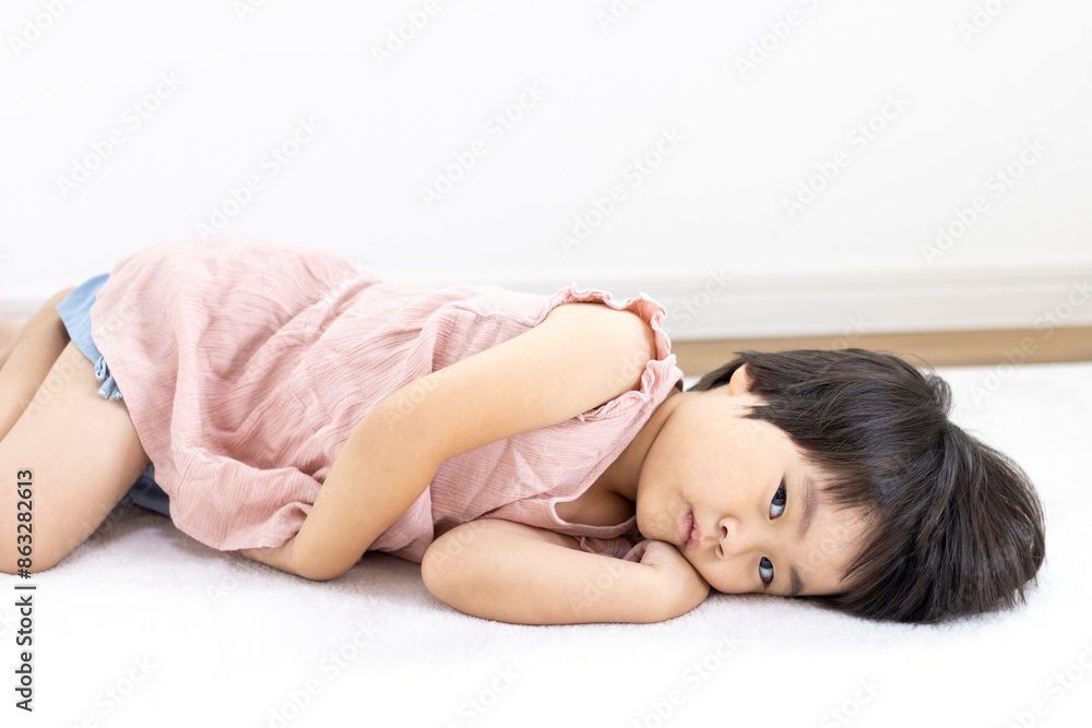 Obraz premium 絨毯に寝転がる笑顔の女の子（3歳、日本人、ショートヘア）