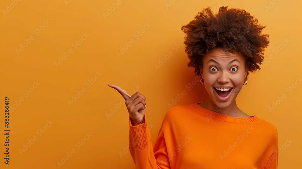 Photo of delighted cheerful Afro American woman with crisp hair, points away, shows blank space, happy to advertise item on sale, wears orange jumper, demonstrates where clothes shop situated Photo of delighted cheerful Afro American woman with crisp hair, points away, shows blank space, happy to advertise item on sale, wears orange jumper, demonstrates where clothes shop situated
