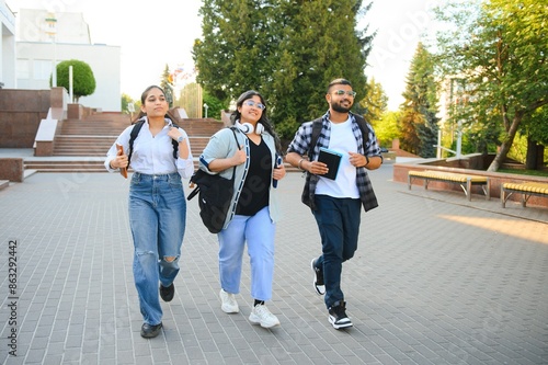 Three international students standing and holding a books