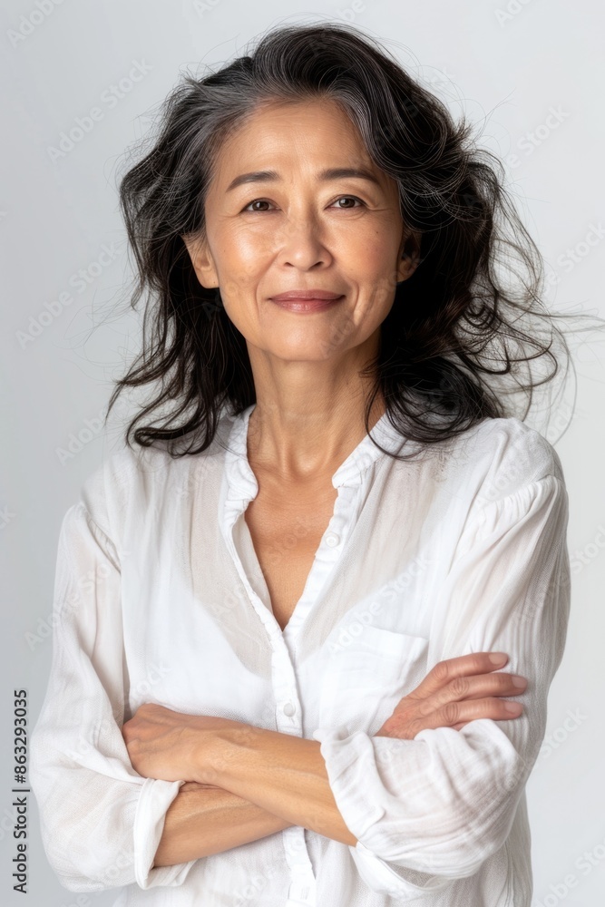 A woman stands with her arms crossed, wearing a white shirt A woman stands with her arms crossed, wearing a white shirt