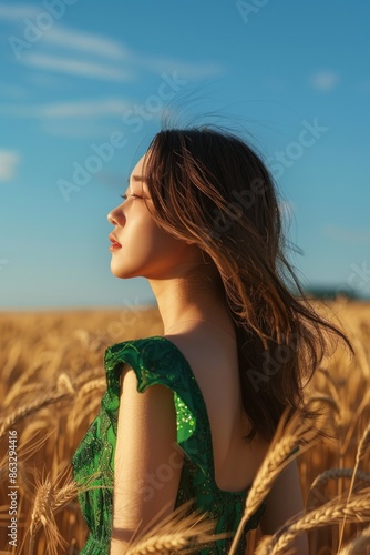 A woman stands alone in a lush wheat field, wearing a bright green dress
