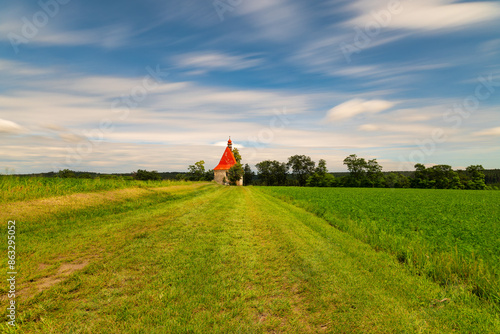 Church of the Assumption of the Virgin Mary in Dobronice near Bechyně. The church was photographed in the summer, in the foreground is a green field and the road to the church photo