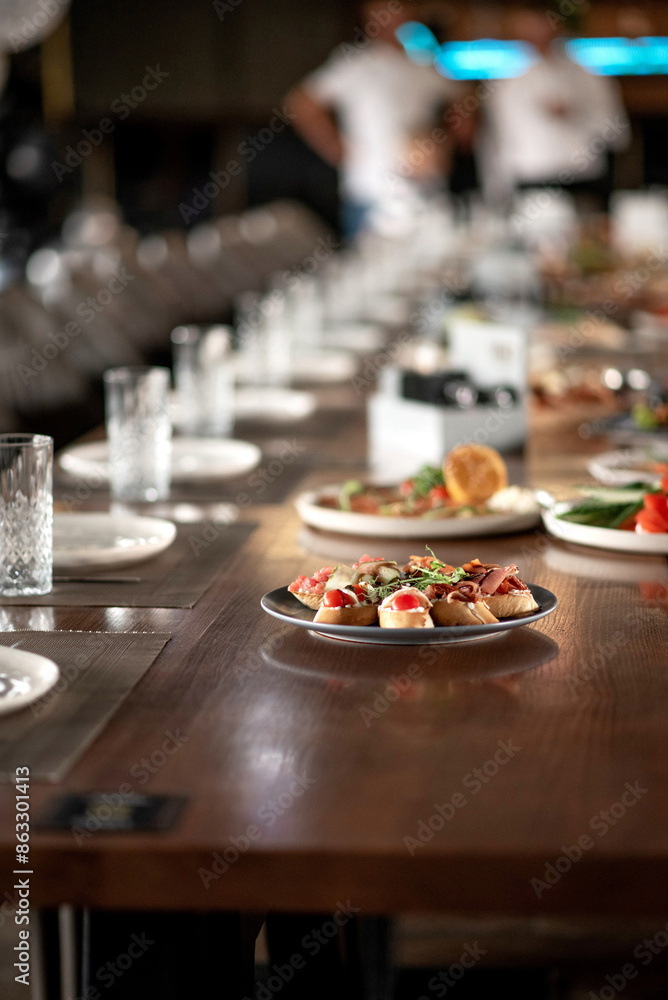 Plate of bruschetta with utensils on a long wooden table in a restaurant Plate of bruschetta with utensils on a long wooden table in a restaurant