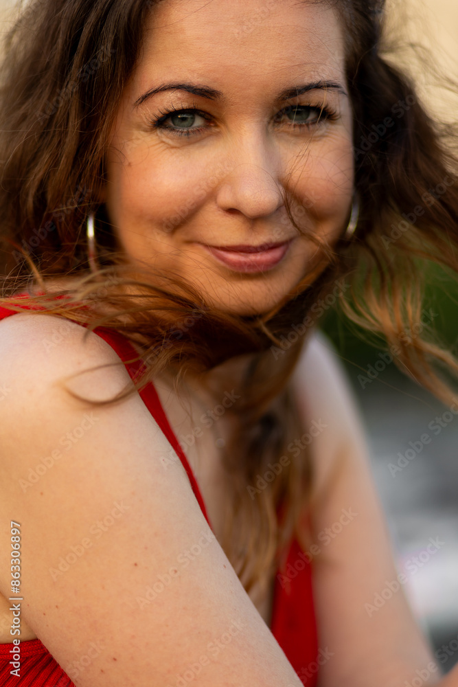 Obraz premium Cute young beautiful attractive woman with long hair in a red dress. Cityscape, urban summer walks, sunset bright sunlight. Happiness, confidence, freedom