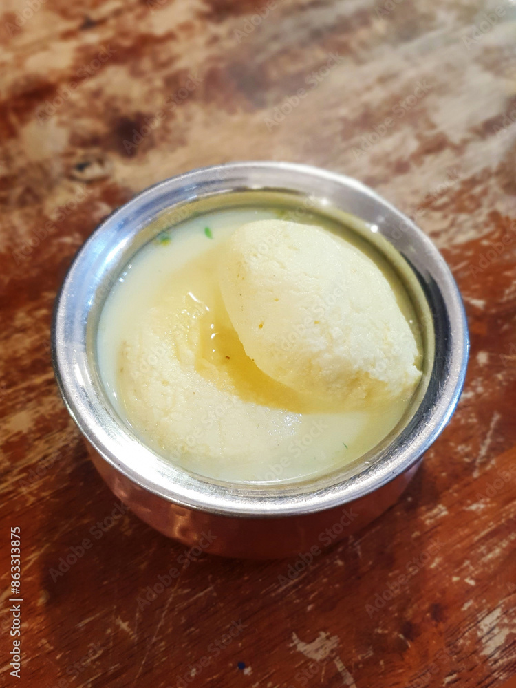 The Indian dessert - Rasmalai on a wooden table. The Indian dessert - Rasmalai on a wooden table.