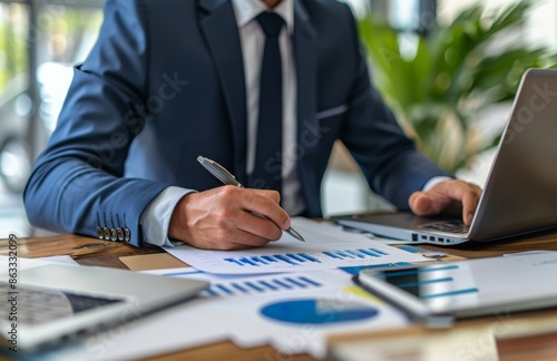 Businessman Working on Laptop With Financial Documents in Office