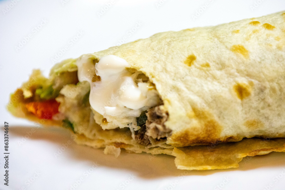 Traditional Shawarma sandwich fresh roll of, Grilled Meat and salad tortilla wrap with white sauce isolated on white background. Details Traditional Shawarma sandwich fresh roll of, Grilled Meat and salad tortilla wrap with white sauce isolated on white background. Details
