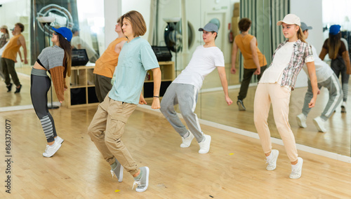 Group of positive teenagers dancing modern dance in ballroom. © JackF