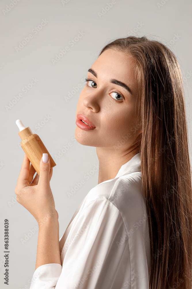Obraz premium Young woman with bottle of natural serum on light background