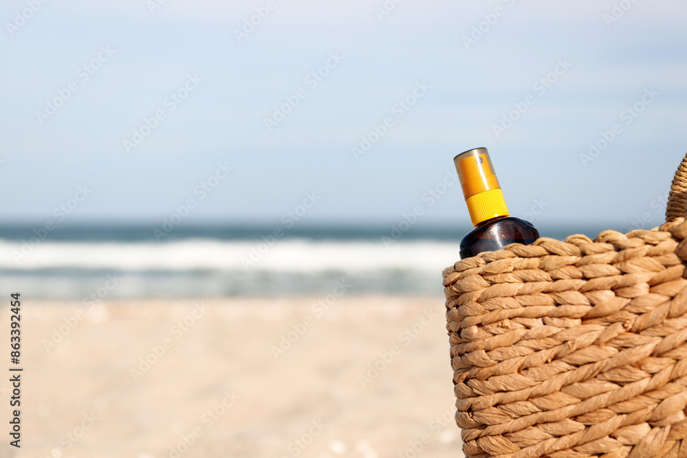 Straw bag with bottle of sunscreen cream, closeup Straw bag with bottle of sunscreen cream, closeup