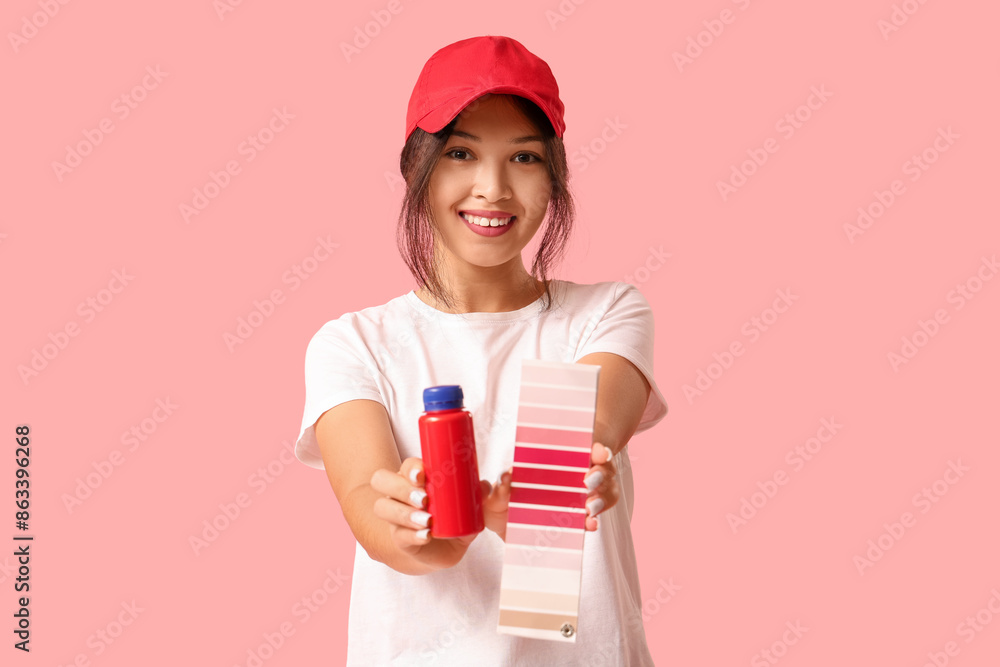 Young woman holding bottle of paint and palette samples on pink background Young woman holding bottle of paint and palette samples on pink background