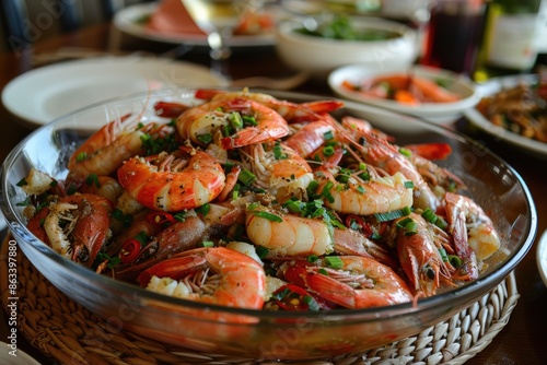 A large bowl of shrimp and onions is on a table. The shrimp are in various sizes and are surrounded by a variety of vegetables. The bowl is placed on a table with other dishes and utensils