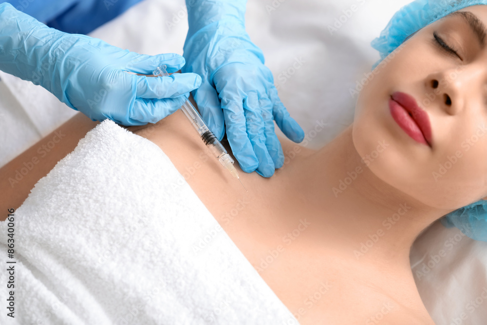 Fototapeta premium Young woman receiving filler injection in beauty salon
