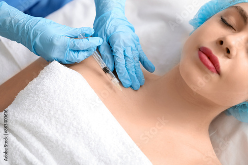 Young woman receiving filler injection in beauty salon