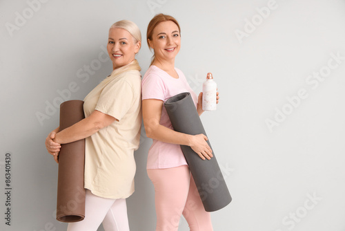 Mature women with yoga mats...