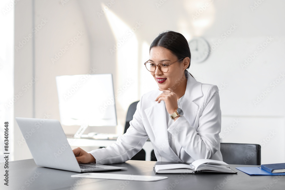 Young Asian businesswoman working with laptop at table in office Young Asian businesswoman working with laptop at table in office