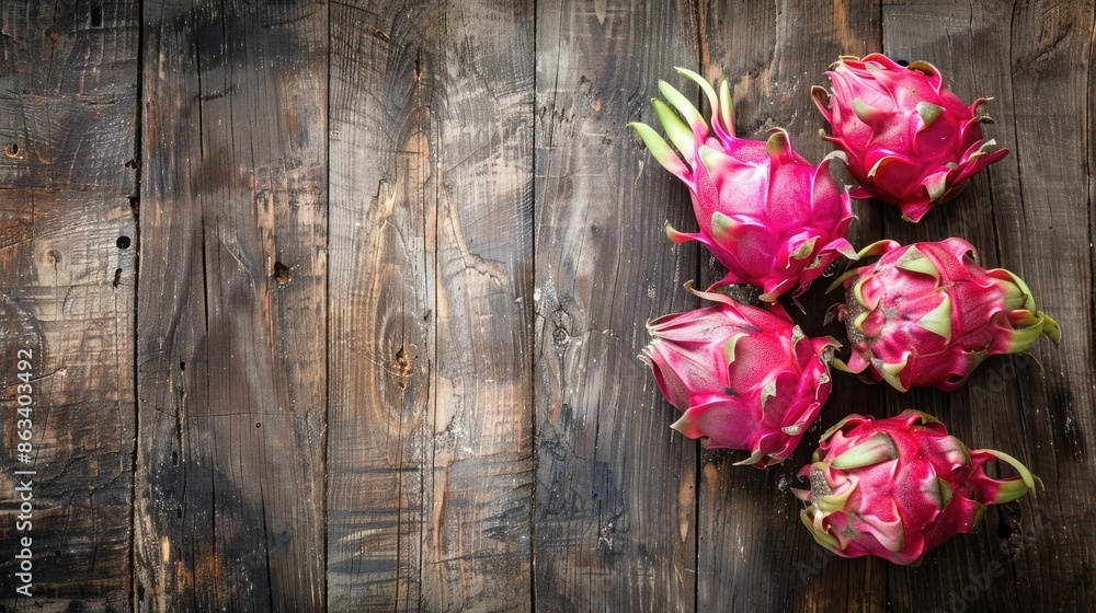 A bunch of red dragon fruit are on a wooden table. The fruit are arranged in a row, with the top one slightly larger than the others. The table is made of wood and has a natural, rustic feel to it A bunch of red dragon fruit are on a wooden table. The fruit are arranged in a row, with the top one slightly larger than the others. The table is made of wood and has a natural, rustic feel to it
