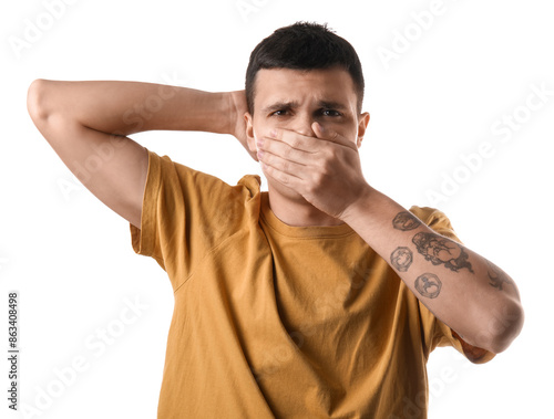 Handsome young man feeling bad smell from armpits on white background photo