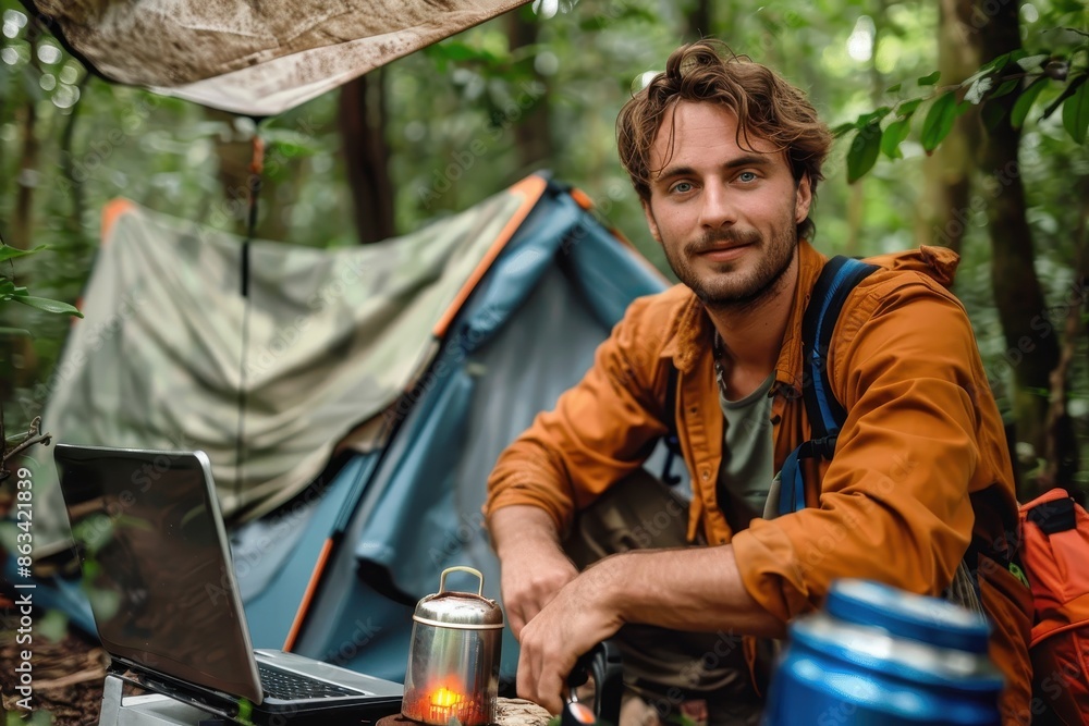 A man in an orange jacket is seated beside a tent in a lush forest, relaxing and using a laptop, with a pot nearby, suggesting a blend of work and wilderness adventure. A man in an orange jacket is seated beside a tent in a lush forest, relaxing and using a laptop, with a pot nearby, suggesting a blend of work and wilderness adventure.