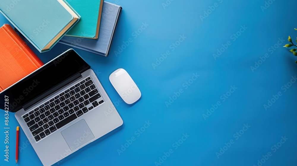 A contemporary learning workspace featuring a laptop, textbooks, and a wireless mouse on a vibrant blue desk. Generative AI A contemporary learning workspace featuring a laptop, textbooks, and a wireless mouse on a vibrant blue desk. Generative AI