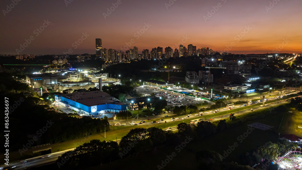 Fototapeta premium Curitiba in Paraná, Brazil. Aerial View. Wonderful sunset with views of buildings and Tanguá Park. Lake with reflection..