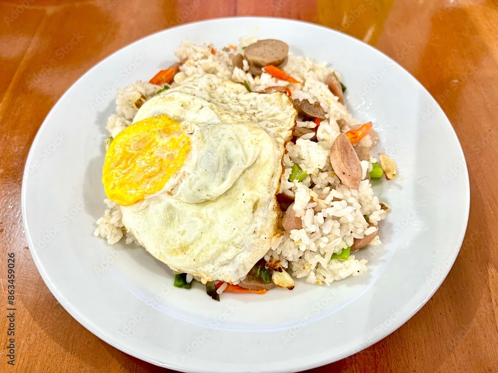 Top view or flat lay shot of homemade Indonesian Fried Rice or Nasi Goreng with meatballs, sausage, and sunny side up egg on a plate Top view or flat lay shot of homemade Indonesian Fried Rice or Nasi Goreng with meatballs, sausage, and sunny side up egg on a plate