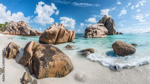 Fototapeta Naklejka Na Ścianę i Meble -  1. The iconic granite boulders of Anse Source d'Argent beach in Seychelles, with crystal-clear turquoise waters lapping against the smooth white sands, under a vibrant blue sky.