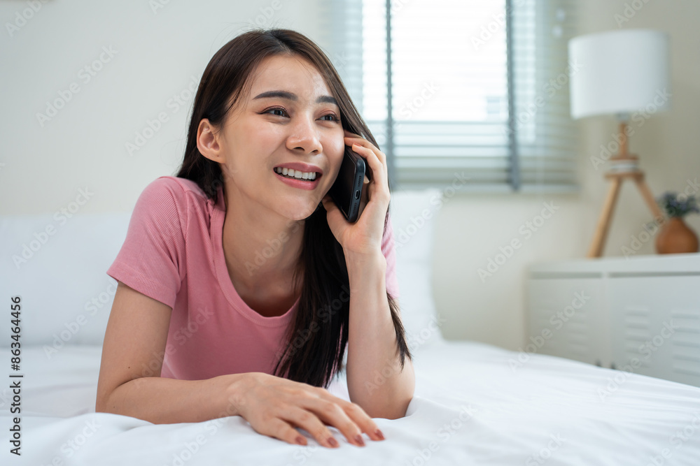Asian attractive woman talking on mobile phone on bed at home in morning. Asian attractive woman talking on mobile phone on bed at home in morning.