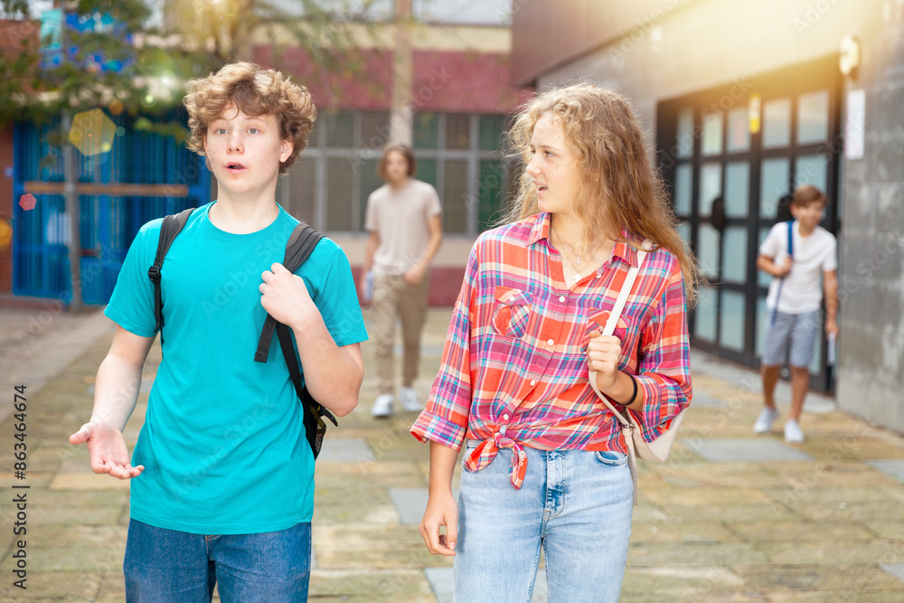 Φωτογραφία Two teenagers boy and girl walking home after finishing college lessons on autum